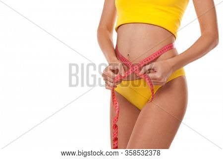 Tanned woman with measure tape isolated on white background. Close up of sporty and beautiful female body. Healthy lifestyle, dieting, fitness, weight loss concept