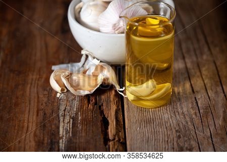 Garlic Oil And Garlic On A Wooden Table.
