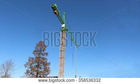 Tower Crane Is Working At A Construction Site. Blue Sky Background.