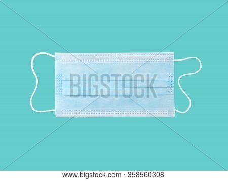 close up single light blue surgical mask (medical face mask) with white rope strap for prevent germs while performing surgery or protective coronavirus (COVID-19) outbreak isolated on cyan background