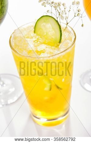 Passion fruit and cucumber cocktail close up. Alcohol drink in glass top view. Beverage with fruit juice, ice tea in drinkware. Summer beach exotic cocktail portion with crushed ice in glassware