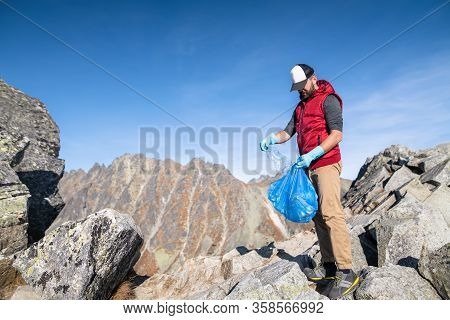 Man Hiker Picking Up Litter In Nature In Mountains, Plogging Concept.