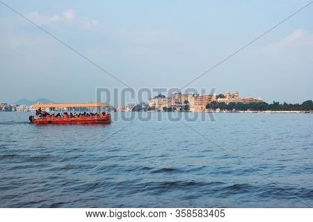 Toruist boat in Lake Pichola with City Palace in background. Udaipur, Rajasthan, India