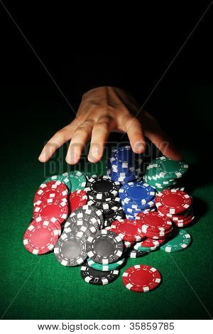 Poker fişleri ve yeşil masa üstündeki el