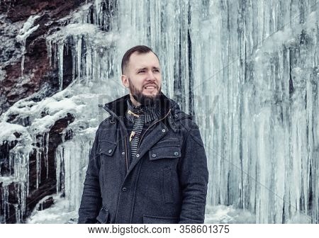 Man standing against cliff full of icicles