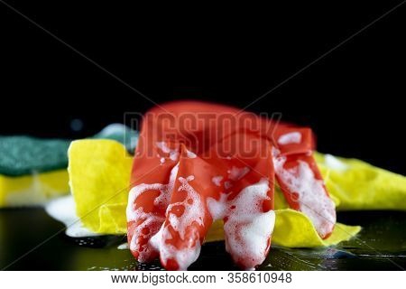 Scouring Sponge Foaming Gloves And Yellow Cleaning Cloth. In Black Background. Close Up.