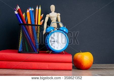 Two Red Books Stand On The Table, On The Books There Are Blue Watches And A Glass With Multi-colored