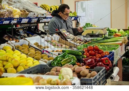 Monte Gordo, Portugal - November 18, 2019: Stallholder Managing His Fresh Produce Stall In The Indoo