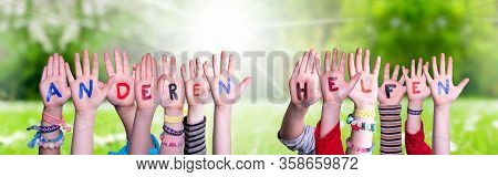 Kids Hands Holding Word Anderen Helfen Means Help Others, Grass Meadow