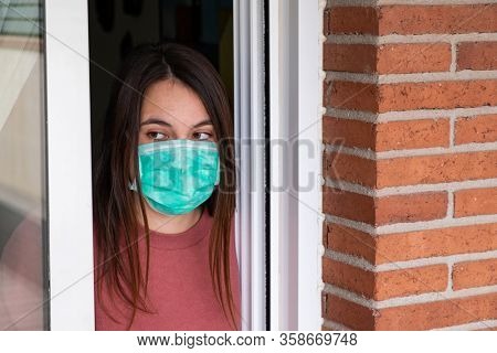young woamn wearing medical mask confined at home. Coronavirus concept