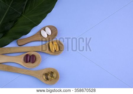 Healthy Supplements On Wooden Teaspoons With Green Leafs On Blue Background