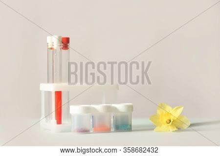 Glass Medical Flasks, Jars With Chemicals And A Yellow Daffodil Flower On A Light Background