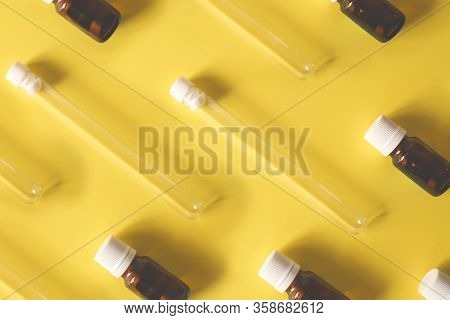 Abstract Background Glass Test Tubes Lie With Vials Of Medicine On A Yellow Background. Medicine, Va