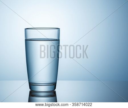 A Glass Of Water Stands On A Smooth, Shiny Surface