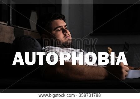 Depressed Overweight Man Eating Sweets On Sofa At Night. Autophobia