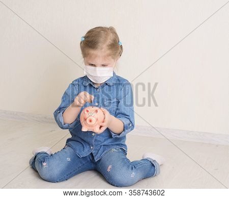 Sad Child Girl In Protective Medicine Mask Holding Piggy Bank. Saving Money Concept. Little Girl Put