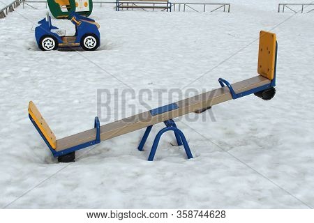 Childrens Swing For Two On The Playground Against The Background Of Winter Snowdrifts. Concept Of Ch