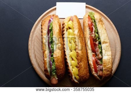 Three Hot Dogs Lying On The Wooden Plate. Mock Up.