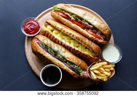 Three Hot Dogs, Sause, Ketchup, Coffee, French Fries Lying On The Wooden Plate.  Mock Up.