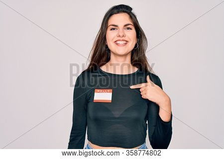Young beautiful girl wearing Hello my name is sticker over isolated background with surprise face pointing finger to himself