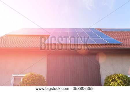 Solar Panels On The Tiled Roof Of The Building In The Sun Set.