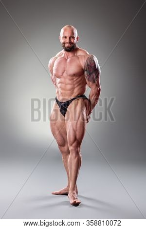 Sexy Muscular Bodybuider Posing On The Gray Background