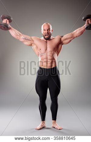 Sexy Muscular Bodybuider Posing With Weights On The Gray Background