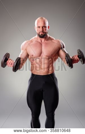 Sexy Muscular Bodybuider Posing With Weights On The Gray Background