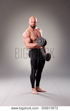 Sexy Muscular Bodybuider Posing With Weights On The Gray Background