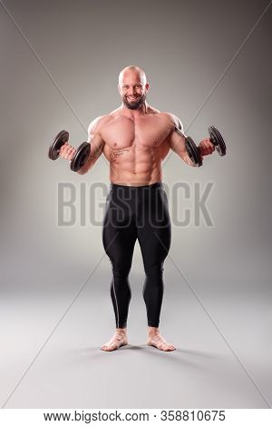Sexy Muscular Bodybuider Posing With Weights On The Gray Background