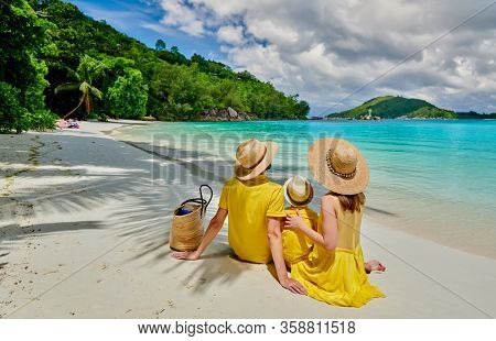 Family on beach, young couple in yellow with three year old boy. Summer vacation at Seychelles. Port Launay, Mahe. 