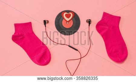 Two Sporty Red Socks, Red Headphones, And A Red Vinyl Disc On A Pink Background. The Concept Of Musi
