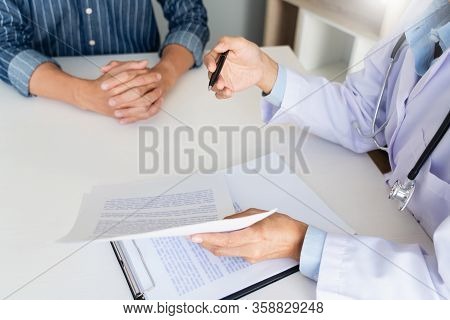 Patient Listening Intently To A Male Doctor Explaining Patient Symptoms Or Asking A Question As They