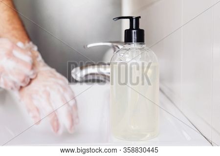 Man Cleaning His Hands Using Liquid Disinfectant Soap And Water In Bathroom.