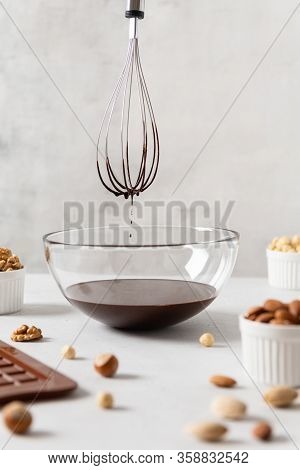 Chocolatier Preparing Chocolate Whisking The Melted Chocolate With A Whisk Dripping Onto The Counter
