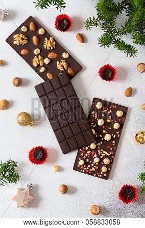 Dark Chocolate Bars With Nuts And Chocolate Candies On White Background With Fir Branches. Homemade 