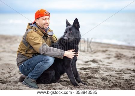 German Black Shepherd With Its Owner On The Sandy Beatch Of Black Sea