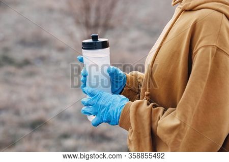 Covid-19 Pandemic Coronavirus Girl In Blue Gloves Holding A Bottle Of Water On A Jog During Coronavi
