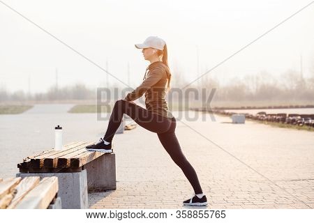 Beautiful Girl At Morning Workout Outdoors In Black Leggings And With A Bottle Of Water