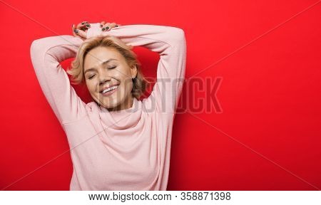 Lovely Caucasian Lady Posing With Hands Up On A Red Wall With Free Space