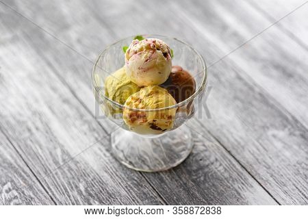 Colored Balls Of Ice Cream In A Glass Cremant On Wooden Grey Background.