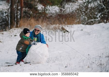 Father And Little Toddler Boy Walking In The Winter Forest And Having Fun With Snow. Family Enjoying
