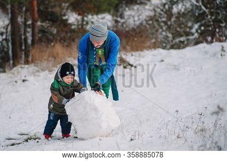 Father And Little Toddler Boy Walking In The Winter Forest And Having Fun With Snow. Family Enjoying