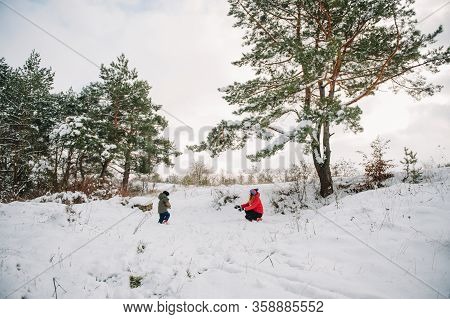 Mother And Little Toddler Boy Walking In The Winter Forest And Having Fun With Snow. Family Enjoying