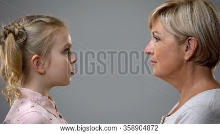 Scared Girl Looking At Strict Grandmother, Difficult Childhood, Generation Gap