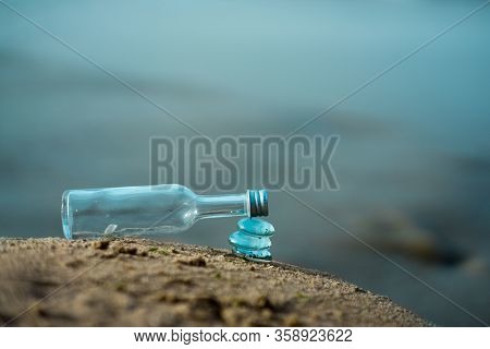 Colorgraded Transparent Bottle On Stack Of Glass Stones Symbolizing Balance