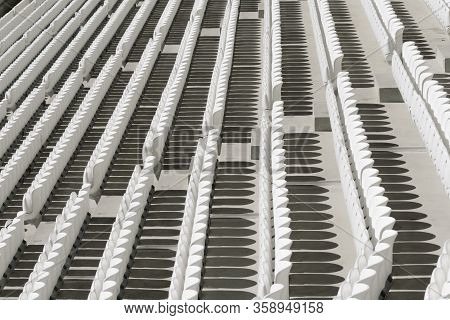 Rows Of White Empty Plastic Seats In A Stadium.