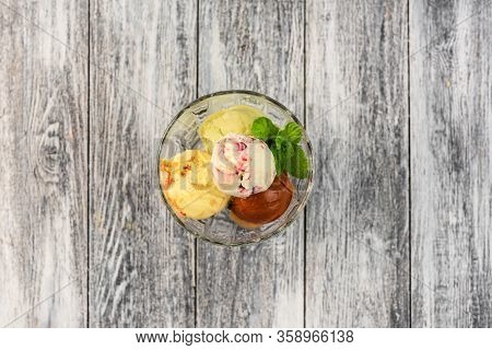 Colored Balls Of Ice Cream In A Glass Cremant On Wooden Grey Background.