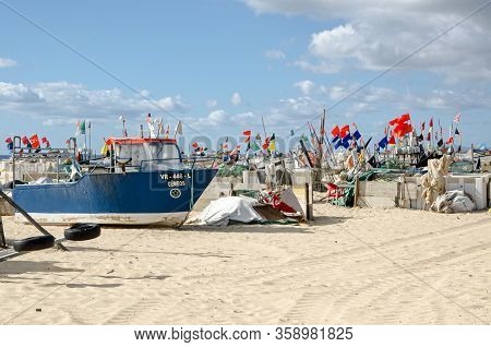 Monte Gordo, Portugal - November 18, 2019:  Fishing Boats, Nets And Markers Resting On The Sandy Bea