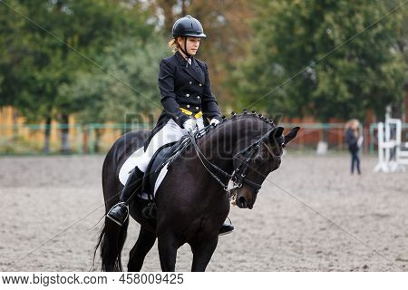 Young Teenage Girl Riding Raven Horse On Dressage Equestrian Event